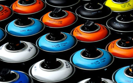Rows of blue, white, orange, and black spray paints