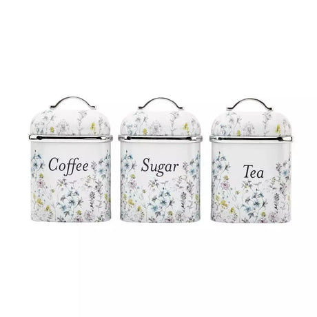 Three white enamel canisters with lids for coffee, sugar, and tea, decorated with a delicate blue and yellow floral pattern.