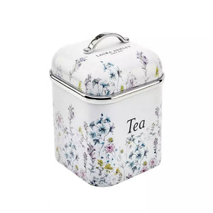 A square white tea canister with a floral print, featuring a silver metal handle and rim, and the words 'LAIN & LEISLEY' and 'Tea' printed on it, set against a plain white background.