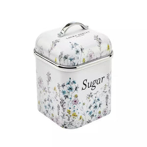 A square metal sugar canister with a hinged lid and top handle, decorated with a delicate multicolor floral pattern on a white background. The word 'Sugar' is printed in black script on the front, and 'LAIR & LEYMENT' is visible near the top of the lid.